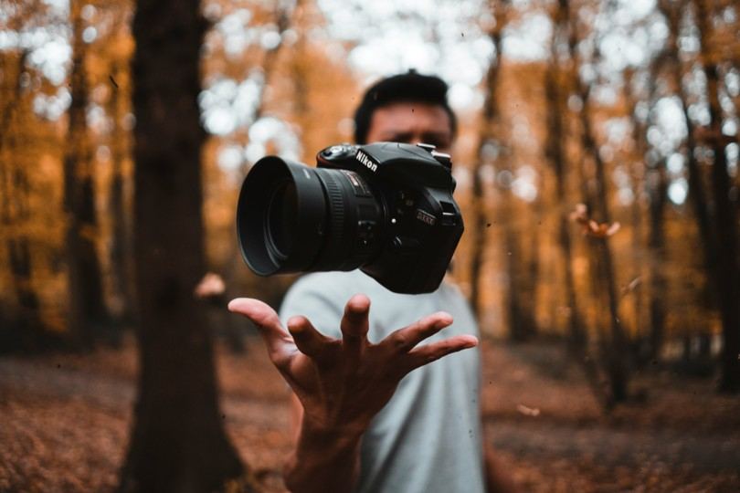 A photographer tossing a camera in a forest setting